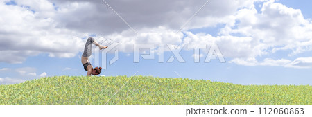 Harmony with Nature: Woman Practicing Yoga in Lush Green Field Under Blue Sky 112060863