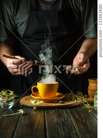 A man prepares tea from the medicinal plants rosehip and chamomile on the kitchen table. Traditional medicine concept at home A man prepares tea from the medicinal plants rosehip and chamomile on the kitchen table. Traditional medicine concept at home 112061680