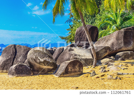 View of large stones, boulders and palm trees on the shore of the South China Sea. Sanya, China. 112061761