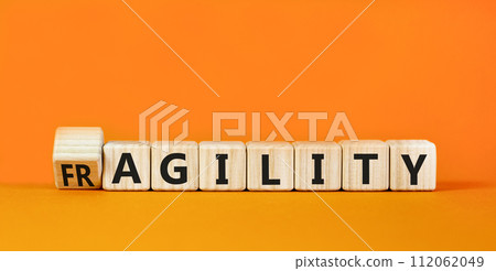 Fragility or agility symbol. Concept words Fragility and Agility on wooden cubes. Beautiful orange table orange background. Business fragility and agility concept. Copy space. 112062049