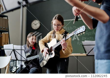 Selective focus shot of girl and her classmates playing instrumental music in classroom at school Selective focus shot of girl and her classmates playing instrumental music in classroom at school 112062245