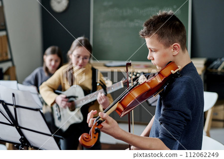 Selective focus shot of modern middle school band practicing music in classroom, copy space Selective focus shot of modern middle school band practicing music in classroom, copy space 112062249