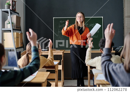 Selective focus shot of children raising their hands willing to answer teachers question during music lesson 112062278