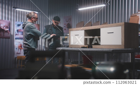 Male designer with digital tablet discusses making TV stand with colleague Male designer with digital tablet discusses making TV stand with colleague 112063021