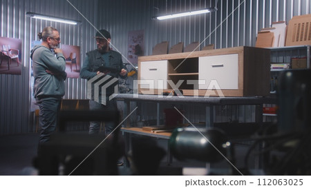 Male carpenter or designer uses tablet computer, talks with customer 112063025