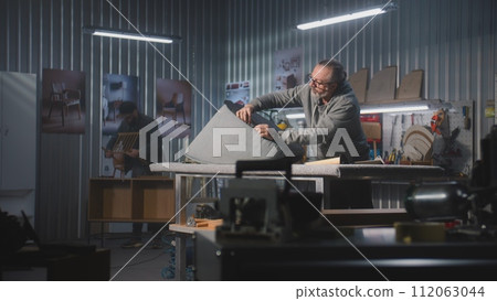 Mature carpenter makes upholstery of chair using staple gun 112063044