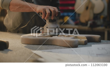Mature carpenter grinding guitar body using grinding machine 112063100