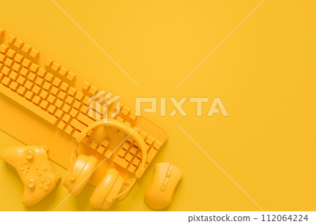 Modern home office setup featuring keyboard, gaming controllers and headphones 112064224