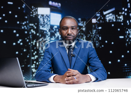 Anchorman hosting night show live on television network, discussing about important information and latest events. African american presenter working in tv broadcast and media industry. Anchorman hosting night show live on television network, discussing about important information and latest events. African american presenter working in tv broadcast and media industry. 112065746
