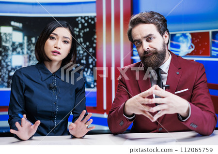 Diverse reporters reading headlines in newsroom, using media outlets to present daily information and insight about events. Journalists team creating live content for newscast reportage. 112065759