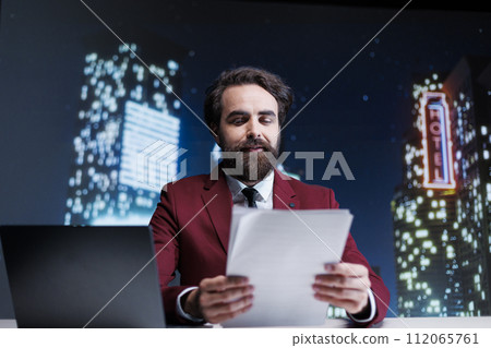 TV presenter reading headlines using media papers on live television night show, creating news reportage for tv content. Journalist reporting daily information about public events. 112065761