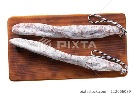 spanish sausage fuet on a wooden cutting board isolated, top view. spanish sausage fuet on a wooden cutting board isolated, top view. 112066089