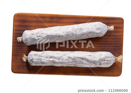 spanish sausage fuet on a wooden cutting board isolated, top view. spanish sausage fuet on a wooden cutting board isolated, top view. 112066090