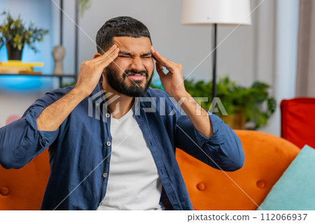 Sick ill Indian man rubbing temples to cure headache problem suffering from tension migraine stress Sick ill Indian man rubbing temples to cure headache problem suffering from tension migraine stress 112066937