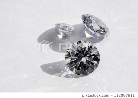 brilliant cut diamond held by tweezers on white background 112067611