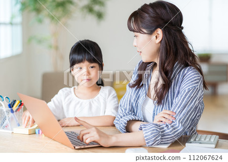一個女孩與在家工作的母親依偎在一起。 112067624