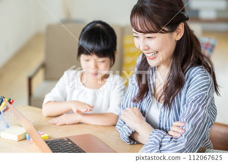 一個女孩與在家工作的母親依偎在一起。 112067625
