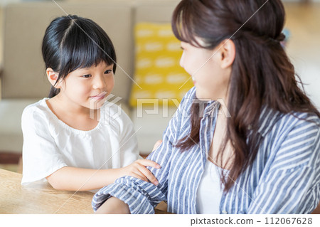 一個女孩與在家工作的母親依偎在一起。 112067628