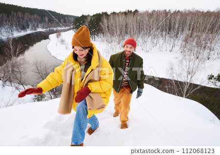 High angle view of active young Caucasian couple hiking on winter day in picturesque place by river High angle view of active young Caucasian couple hiking on winter day in picturesque place by river 112068123