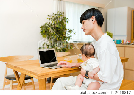 A father working while holding a 0-year-old baby in the living room 112068817