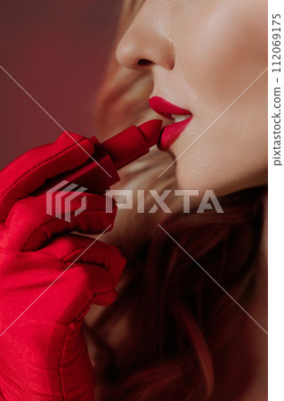 A woman applies red lipstick. Close-up side view. A woman applies red lipstick. Close-up side view. 112069175