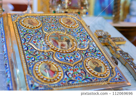 A closeup shot of a decorative red Bible with a gold cross in a church. High quality photo 112069696
