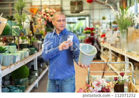 Man photographing flower pot in store 112071252