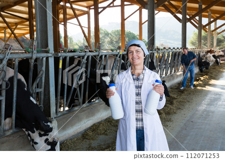Adult woman is standing in uniform and checking the quality of milk 112071253