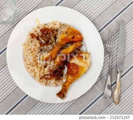 Boiled rice with vegetable gravy and piece of fried chicken is served on large white platter Boiled rice with vegetable gravy and piece of fried chicken is served on large white platter 112071287