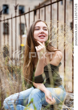 Woman in unbuttoned blouse posing near fence Woman in unbuttoned blouse posing near fence 112071528