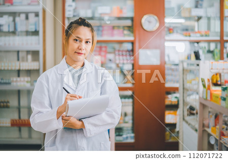 female pharmacist poses confidently welcoming, advising patients and prescription patients in a modern pharmacy. 112071722