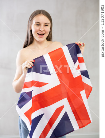 Girl holds unfolded canvas flag of Great Britain in front of her 112071902
