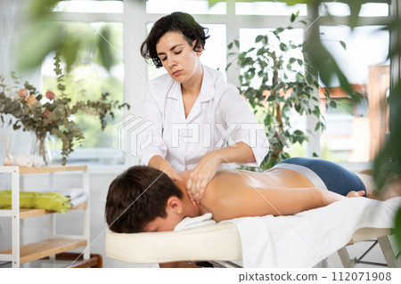 Adult woman giving back massage to young guy 112071908