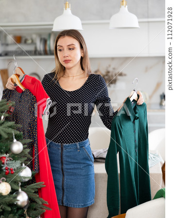 Young upset woman choosing which dress to wear 112071928