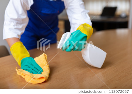 Worker cleaning table with rag and detergent Worker cleaning table with rag and detergent 112072067