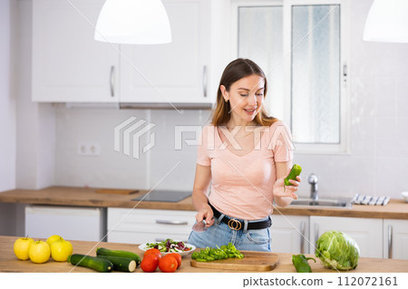 Woman cutting vegetables for salad at kitchen Woman cutting vegetables for salad at kitchen 112072161