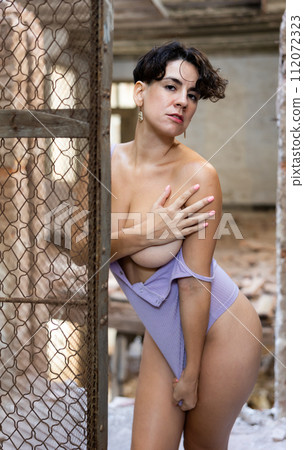 Portrait of naked brunette latino woman posing seductively in a ruined building in t-shirt 112072323