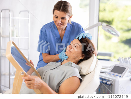 Female aesthetician consulting elderly woman before hardware facial skin treatments Female aesthetician consulting elderly woman before hardware facial skin treatments 112072349