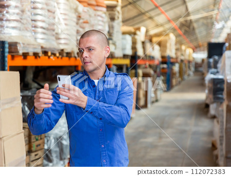 Fulfillment center worker using smartphone in his work 112072383