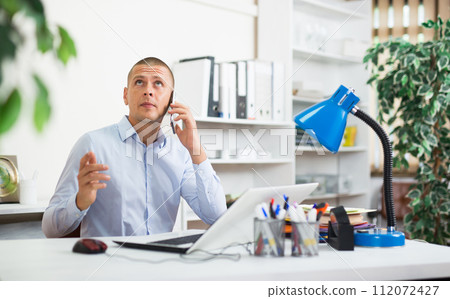 Businessman is talking phone with partner in office 112072427