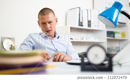 Carefree office worker playing with coin at workplace 112072470