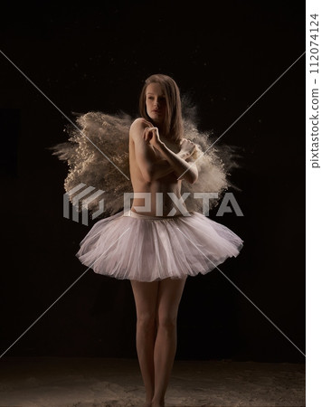 Graceful ballerina dancing in the sand in dark room Graceful ballerina dancing in the sand in dark room 112074124