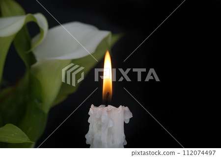 White calla lily flowers and burning wax candle in darkness White calla lily flowers and burning wax candle in darkness 112074497