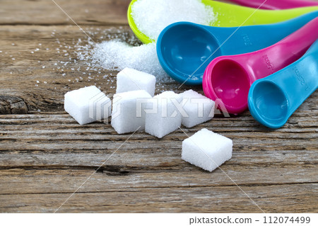 Measuring utensils and spilled sugar on rustic wood Measuring utensils and spilled sugar on rustic wood 112074499