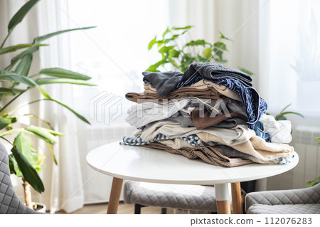 Recycling or donation concept. A stack of clothes lies on the table at home. 112076283