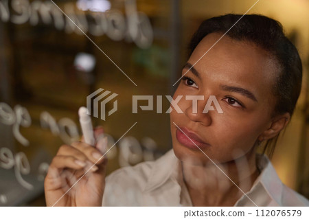 Young Black Woman developing code writing it on glass wall 112076579