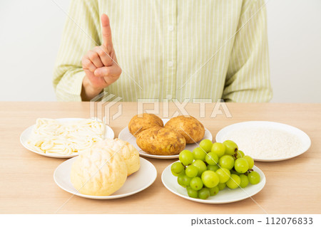 一位中年婦女用食指指著含有大量糖（碳水化合物）的食物 112076833