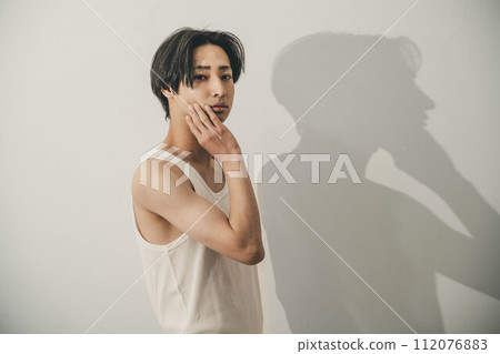 A young man in a tank top posing against a white background 112076883