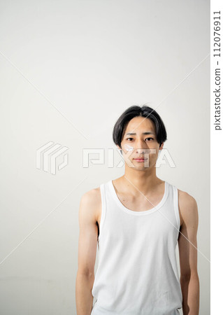一個穿著背心的年輕人在白色背景下擺姿勢 一個穿著背心的年輕人在白色背景下擺姿勢 112076911