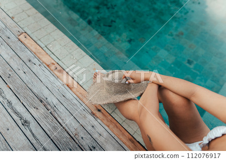 Travel vacation Woman in swimsuit at hotel relaxing pool on island 112076917